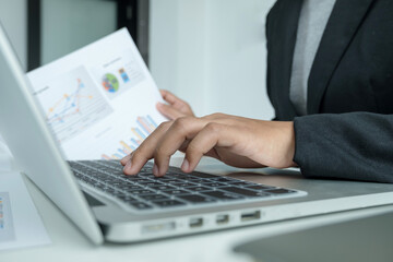 The hands of a male businesswoman are analyzing and calculating the annual income and expenses in a financial graph that shows results To summarize balances overall in office