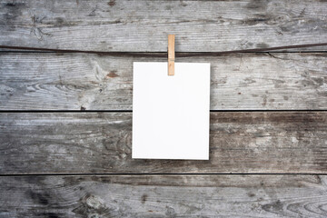 clothespin hanging with blank paper on wooden background
