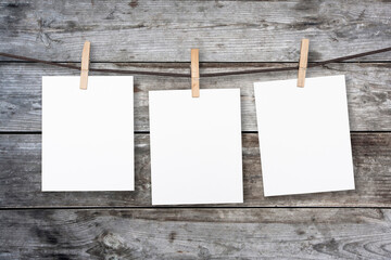 clothespin hanging with blank paper on wooden background
