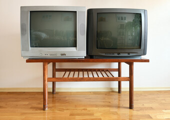Two outdated vintage HORIZON TVs sit on a vintage table in a 1990s apartment block.