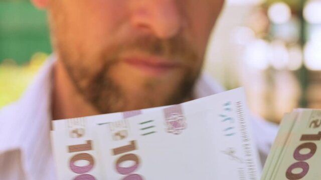 Cinematic shot: Men's hands consider Ukrainian money with a nominal value of one thousand hryvnias. Person counts banknotes. Man counts a large wad of money. Human hands with money