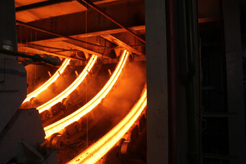 Red hot steel metal billets after molten steel casting.  Continuous casting machine. Background of...