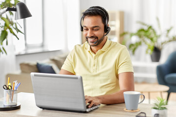 remote job, technology and people concept - happy smiling indian man with headset and laptop computer having conference call at home office