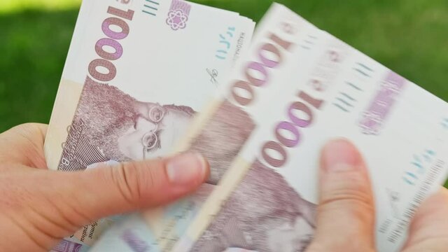 Cinematic shot: Men's hands consider Ukrainian money with a nominal value of one thousand hryvnias. Person counts banknotes. Man counts a large wad of money. Human hands with money