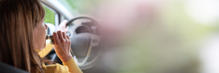 Woman smoking an e-cigarette in car; panoramic banner
