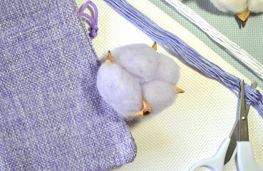Tender lavender pastel composition of organic cotton flowers, white canvas and cotton mouline threads. Hypoallergic products for cross-stitch embroidery. Hobby. DIY. Closeup    