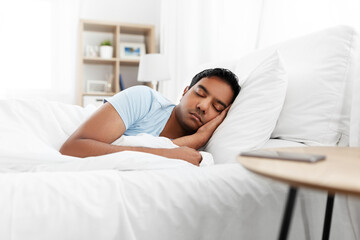 people, bedtime and rest concept - indian man sleeping in bed at home