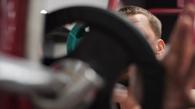Man powerlifter putting pancakes on bar in bodybuilding training in gym. Bodubuilder using weight pancakes for weight barbell on power training in fitness