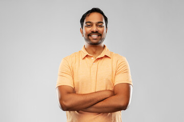 people and furniture concept - portrait of happy smiling young indian man with crossed arms over...