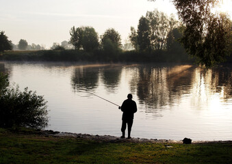 Obraz na płótnie Canvas Fisherman catches fish with a fishing rod in the early morning