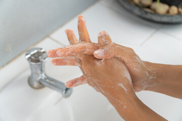 Hands of girl use soap and washing under the water tap. Hygiene concept hand detail. woman washing hands with soap over sink in bathroom.