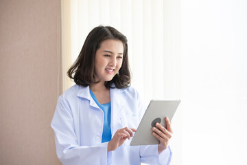 Asian female doctor use tablet in office hospital. Confident woman doctor stand at office desk, health care and prevention technology concept - Powered by Adobe