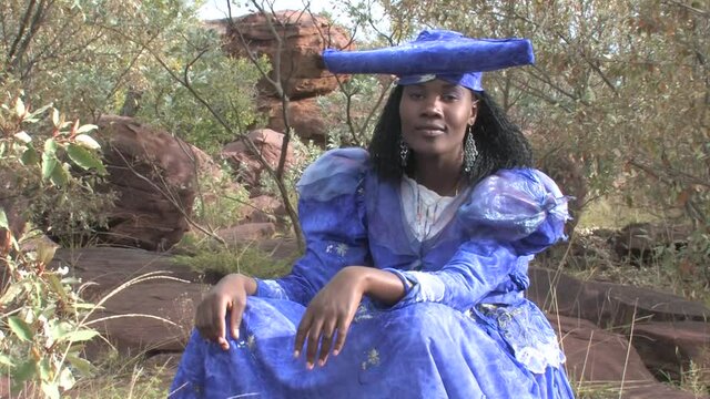 herero woman wearing a Victorian style dress outdoors in a village in north Botswana