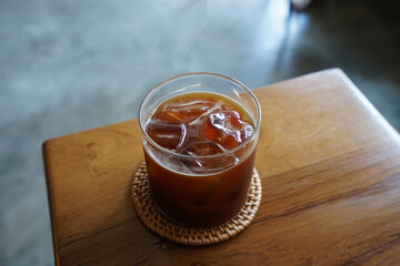 Close up glass of iced black Americano coffee on wooden tray table