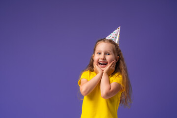happy Birthday! a little girl in a festive hat for her birthday on a purple background.