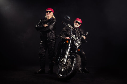 Full body photo of old bikers man lady couple drive chopper travel feel young rock moto festival arms crossed wear rocker leather outfit sunglass bandana isolated black color background