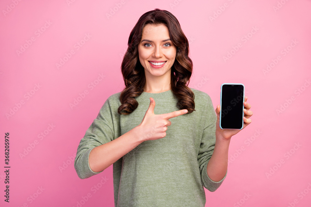 Wall mural portrait of positive cheerful girl promoter hold smartphone new device point index finger recommend 