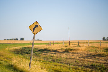 Traffic Signs Right Curve Road Warning in front of bright green and yellow grass on the side of...