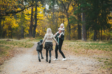 Mom, dad, children walk in the autumn park.