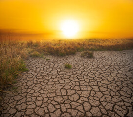 Global warming and climate change. Cracked dry land without water  against golden afternoon sky and...