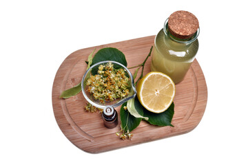 Fresh healthy linden flowers, lemon and tea with essential oil on a white background