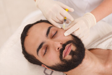 Obraz na płótnie Canvas Top view close up of a bearded man getting anti-ageing filler injections at beauty clinic