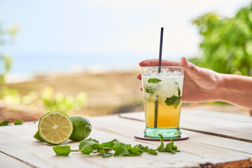 Mojito ready to drink with the beach in the background. Drinking concept for summer.