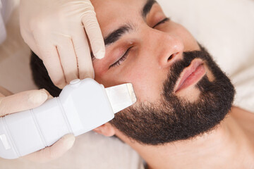 Cropped close up of a male client getting ultrasound cleanse at beauty salon