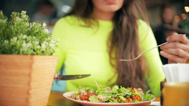 Unknown beautiful young woman eats vegetarian salad in a cafe. Healthy eating concept