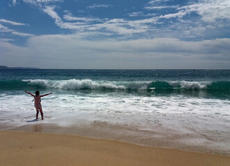 The girl enjoys the Atlantic ocean and the waves in the city of Nazare in Portugal