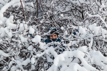 winter park, the child smiles inside a snow-covered Bush