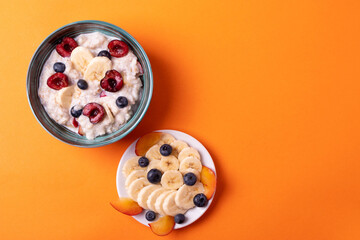 healthy breakfast concept with oat porridge and fruit on orange background