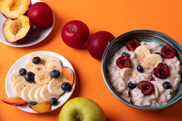 healthy breakfast concept with oat porridge and fruit on orange background