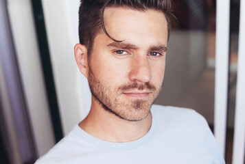 Obraz premium A portrait of a young casual man looking at the camera, sitting on a balcony, looking relaxed and content
