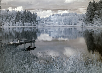 landscape photographed with infrared filter, trees look like in winter, beautiful cloud reflections in the water, surreal landscape