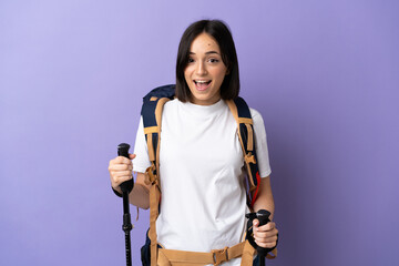 Young caucasian woman with backpack and trekking poles isolated on blue background with surprise facial expression