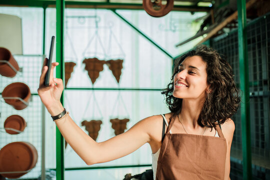 Woman taking a selfie in her small ceramic shop