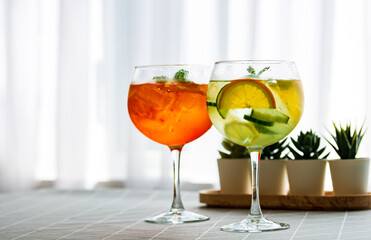 Close-up colorful aperol spritz drink and  gin tonic cocktails in wine glasses on the table at home, afternoon drinks at home, after work drink
