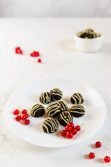 Vegan chocolates garnished with red currants on a white plate. Sugar, lactose, gluten free.