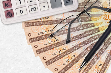 20 Dominican peso bills fan and calculator with glasses and pen. Business loan or tax payment...
