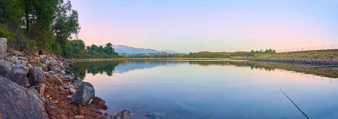 Panoramic large format summer landscape of a large lake with the mountains in the background and a...