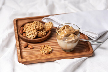 
Delicious cookies, coffee mousse and almonds on a wooden tray.