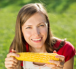 Smiling woman eating sweet  corn