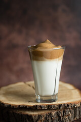 Dalgona cold coffee with milk and foam, on a cut wooden board, instant coffee, Korean trend home-made coffee recipe