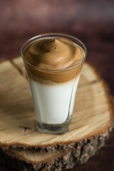 Dalgona cold coffee with milk and foam, on a cut wooden board, instant coffee, Korean trend home-made coffee recipe