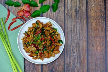 Stir fry pork with lemongrass and chilli surrounded by key ingredients on wooden table. Authentic Thai food.