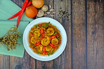 Stir fried shrimps with curry powder surrounded with key ingredients on wooden table. Thai Food.