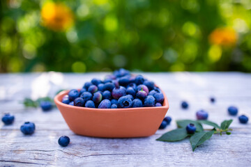 Ripe blueberries in a heart-shaped bowl on a wooden table.