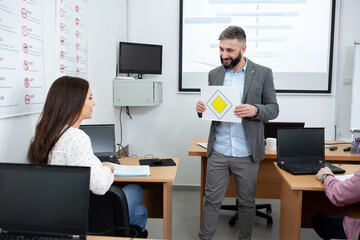 Driving instructor holding a sign of priority road