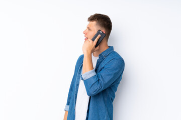 Young handsome man over isolated white background keeping a conversation with the mobile phone with someone